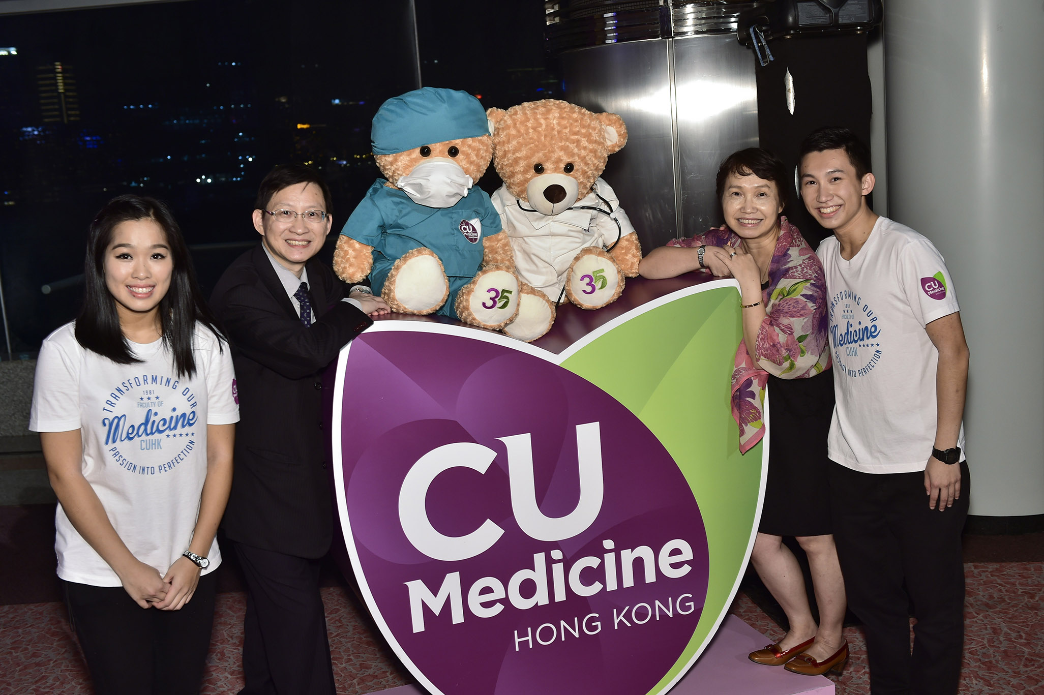Guests take photo in front of the Faculty logo with medic and surgeon bears.